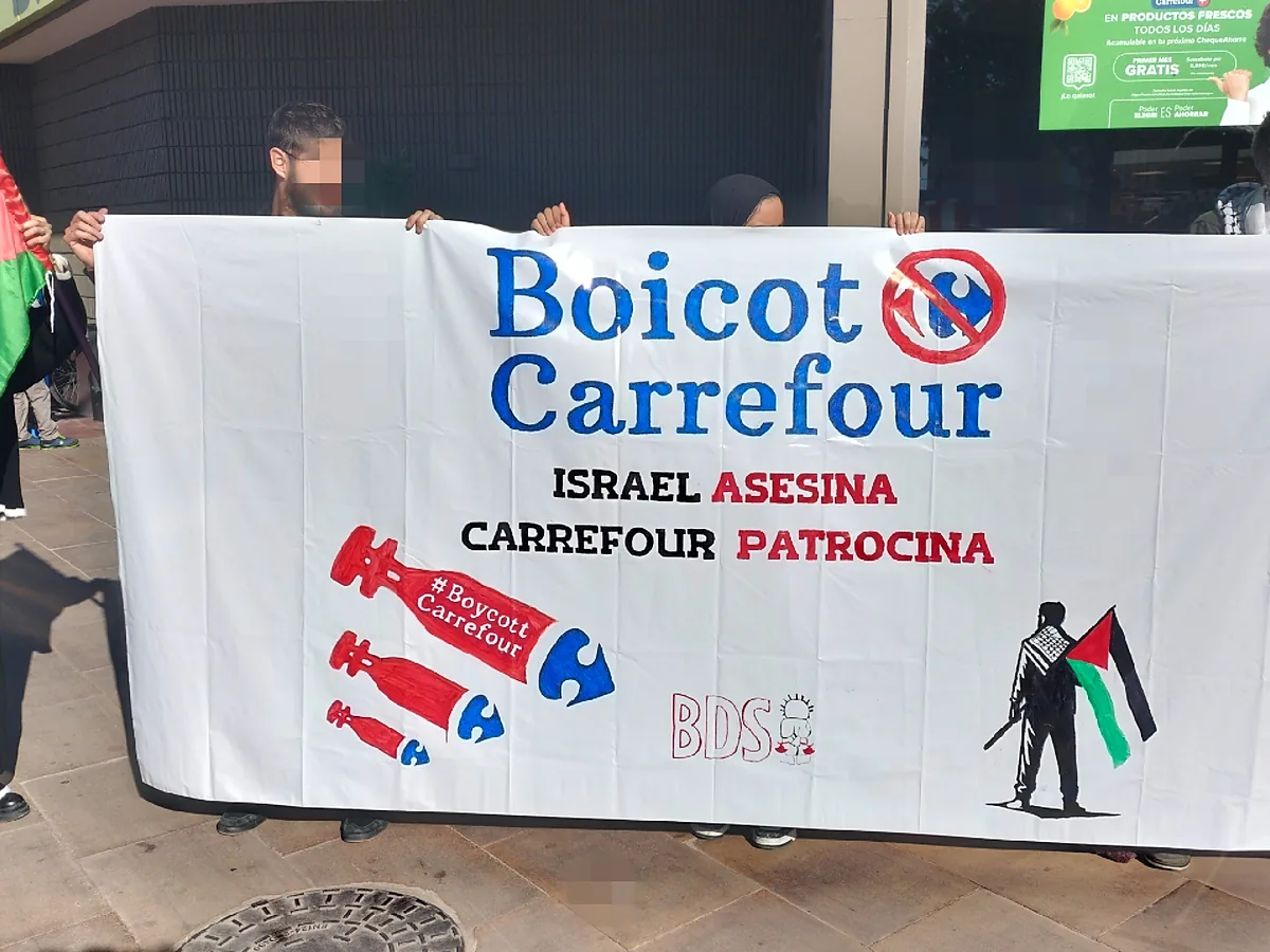 Dua orang membentangkan spanduk kampanye BDS bertuliskan Boicot Carrefour di depan sebuah gerai di Spanyol