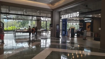 Pintu masuk Samsung Experience Store di dalam mal Senayan Park, Jakarta, dengan logo SAMSUNG menyala dan meja pajangan perangkat