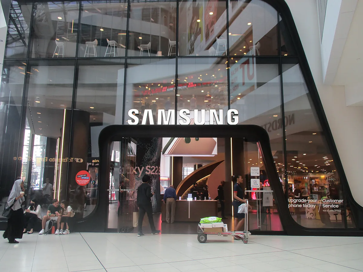 Pintu masuk gerai resmi Samsung di sebuah pusat perbelanjaan dengan papan nama SAMSUNG besar
