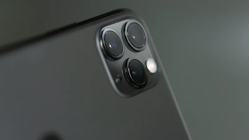 Dekat modul tiga kamera di punggung iPhone 11 Pro berwarna gelap, lengkap dengan lampu kilat dan mikrofon