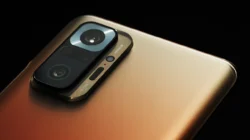 Modul kamera belakang Redmi Note 10 Pro berwarna perunggu dengan empat lensa dalam satu kotak persegi panjang, difoto dari dekat dengan latar hitam