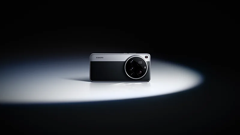 Punggung Xiaomi 15 Ultra hitam dengan pelat atas abu-abu muda dan modul kamera bulat besar berlabel Leica, berdiri tegak di bawah sorot lampu bundar pada latar hitam