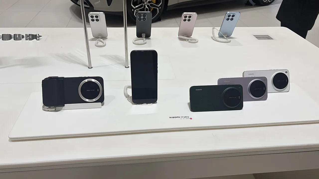 Deretan unit pajangan Xiaomi 17 Ultra di meja gerai, label bertuliskan xiaomi 17 Ultra dengan titik merah Leica, satu unit terpasang aksesori grip kamera Leica, beberapa unit Xiaomi lain digantung di penyangga pada baris belakang