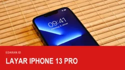 iPhone 13 Pro menyala di atas tikar bambu memperlihatkan poni dan layarnya, dengan teks judul Layar iPhone 13 Pro