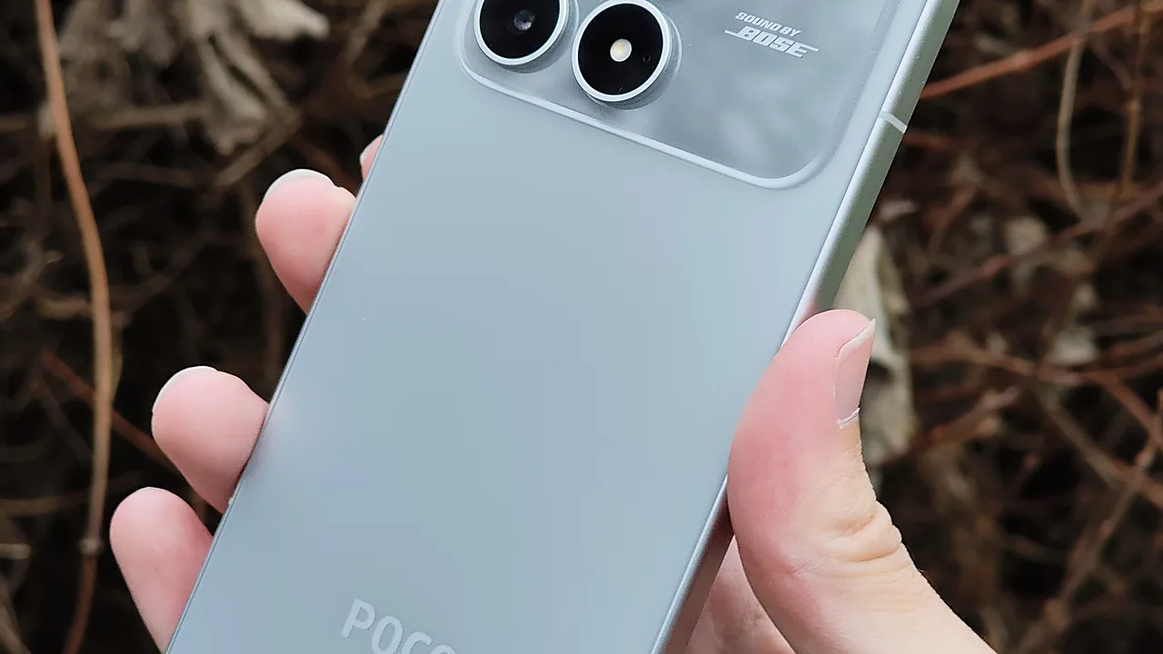 Tangan memegang POCO F8 Pro warna hijau keabuan dari dekat, tampak sebagian modul kamera belakang bertanda Sound by Bose dan logo POCO di bodi bawah
