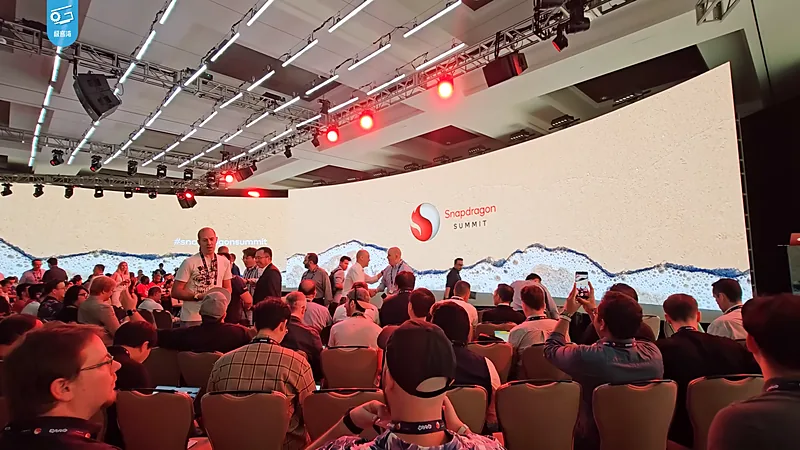 Panggung Snapdragon Summit dengan layar lebar bertuliskan Snapdragon Summit dan ruangan penuh peserta